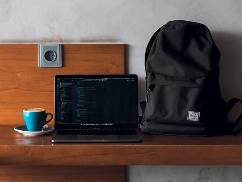 laptop computer beside backpack and coffee mug