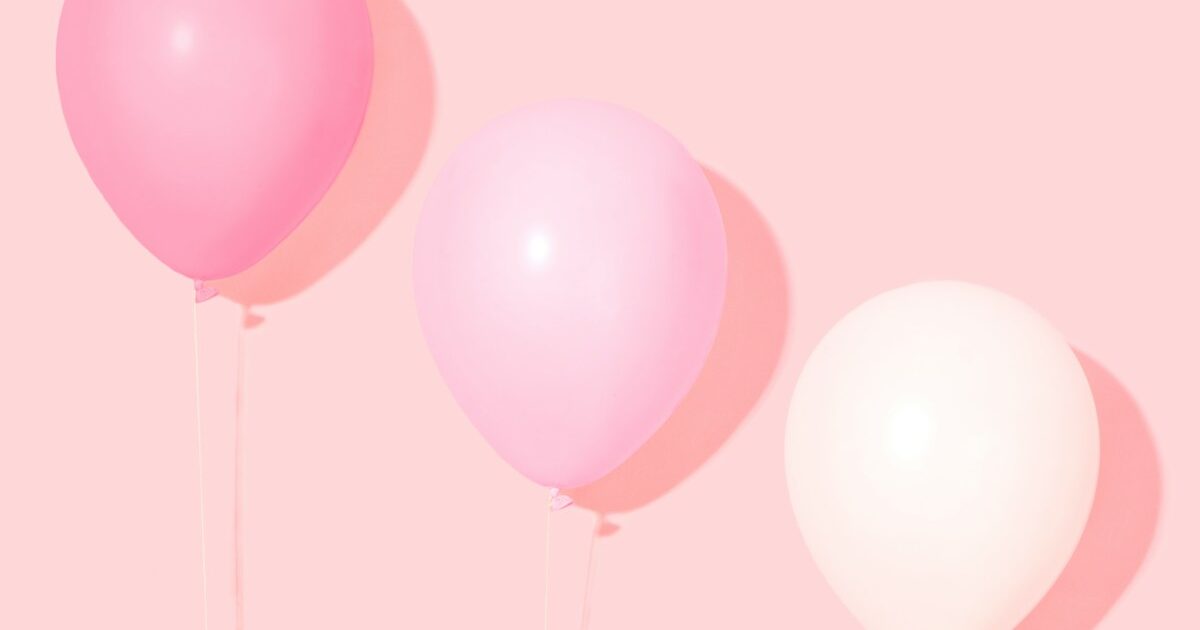 person holding pink and white balloon